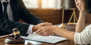 Phoenix car accident lawyer shaking hands with a client over a desk with legal documents.